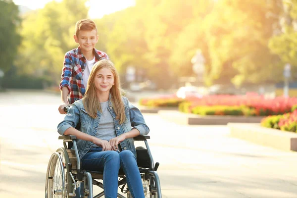Tekerlekli sandalye ve kardeşi açık havada Genç kız — Stok fotoğraf