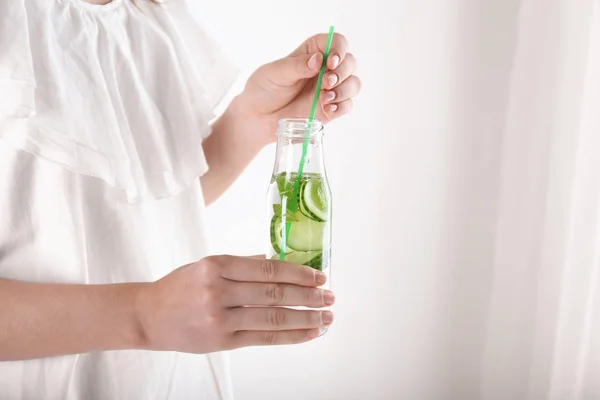 Woman holding bottle with tasty fresh cucumber water and straw — Stock Photo, Image