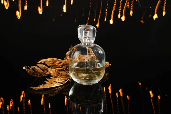 一瓶香水与金黄的叶子和闪闪发光的深色背景 — 图库照片