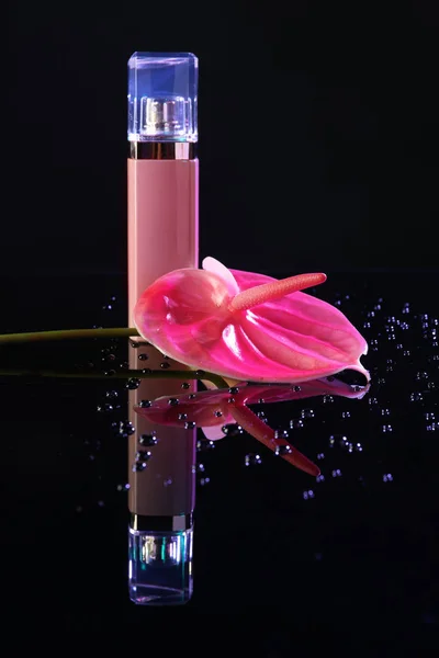 Garrafa de perfume com flor tropical no fundo escuro — Fotografia de Stock