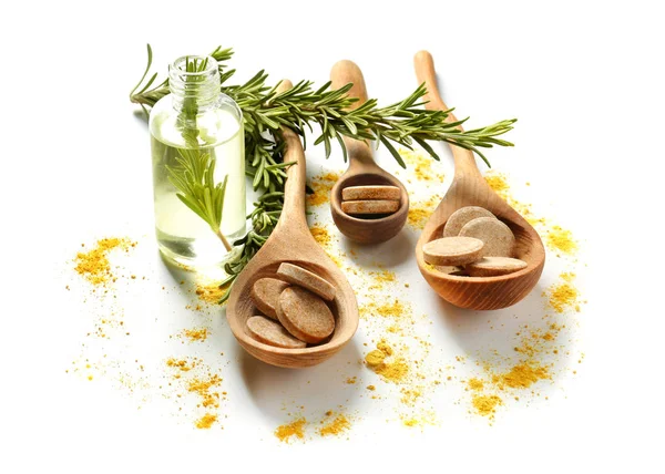 Holzlöffel mit Tabletten, Rosmarin und ätherischem Öl auf weißem Hintergrund — Stockfoto