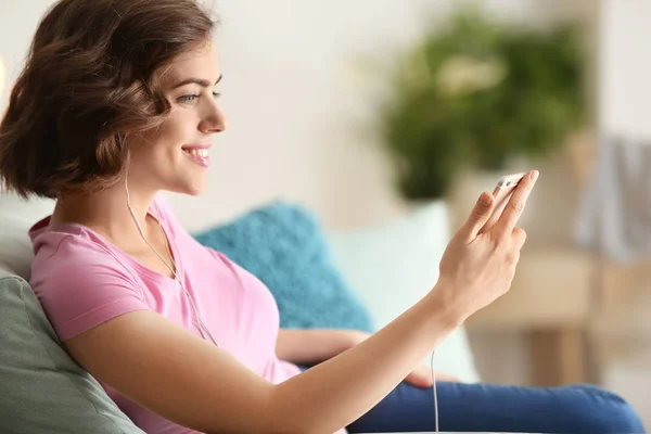 Portrait de belle jeune femme avec téléphone portable écoutant de la musique à la maison — Photo