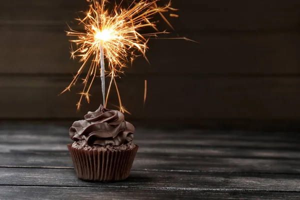 Gustoso cupcake al cioccolato con sparkler sul tavolo di legno — Foto Stock