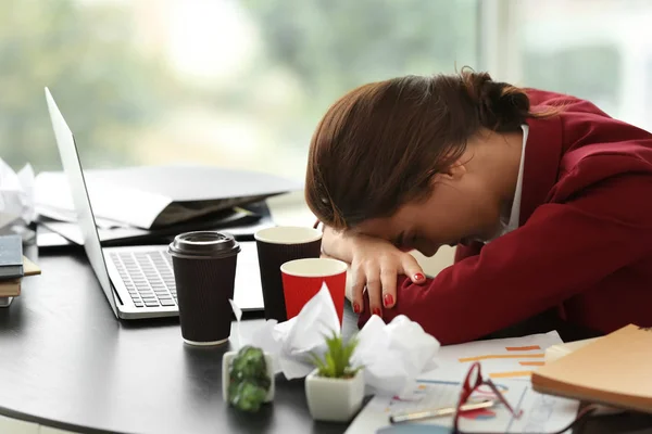 Trabalhador cansado com muito trabalho sentado à mesa no escritório — Fotografia de Stock