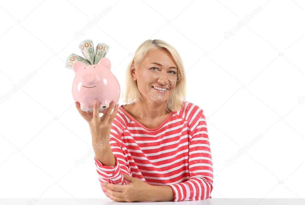 Mature woman with piggy bank on white background