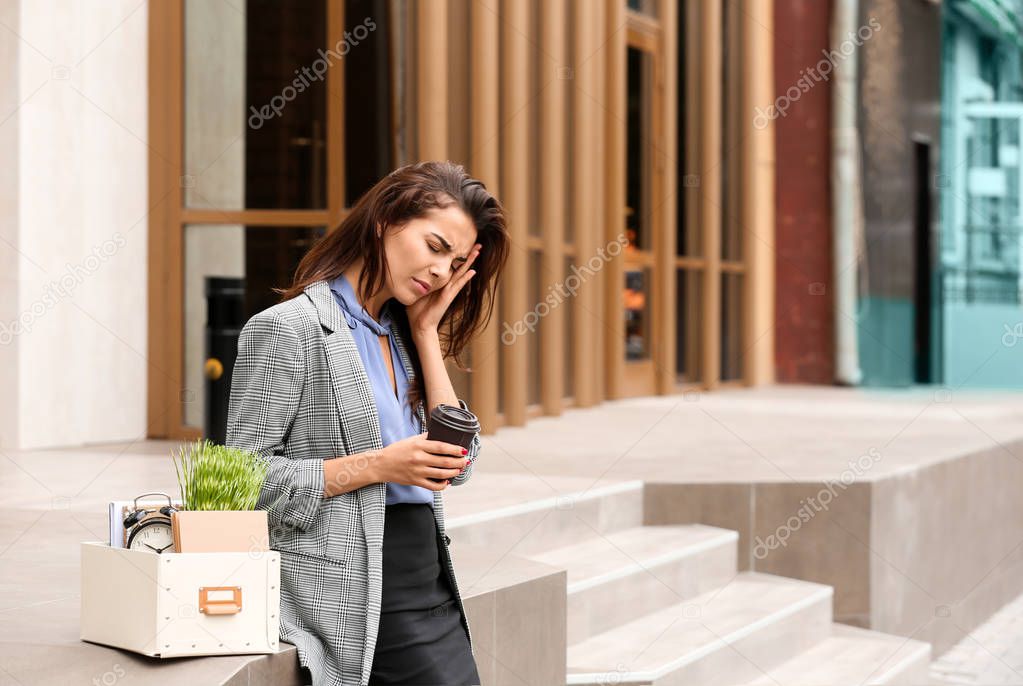 Fired stressed woman with personal stuff and coffee outdoors