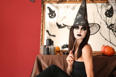 Cadılar Bayramı için dekore edilmiş oda cadı gibi giyinmiş güzel kadın