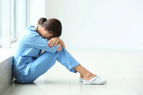 Infermiera stanca seduta sul pavimento in ospedale — Foto Stock