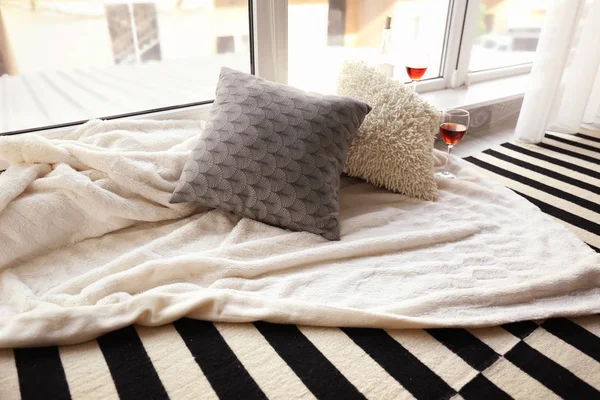 Уютное место для отдыха с мягкими подушками и вином у окна — стоковое фото