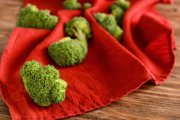 Fresh broccoli with color napkin on wooden background — Stock Photo, Image