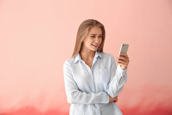 Jonge vrouw met mobiele telefoon op kleur achtergrond — Stockfoto