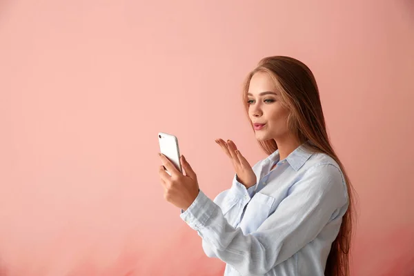 Young woman with mobile phone having online dating on color background — Stock Photo, Image