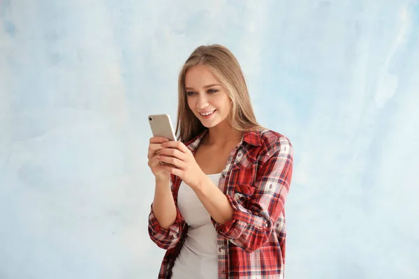 Young woman with mobile phone on light background — Stock Photo, Image