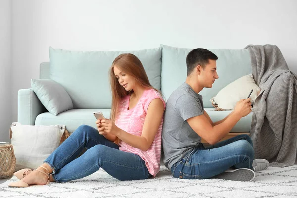 Молодая пара с мобильными телефонами дома — стоковое фото