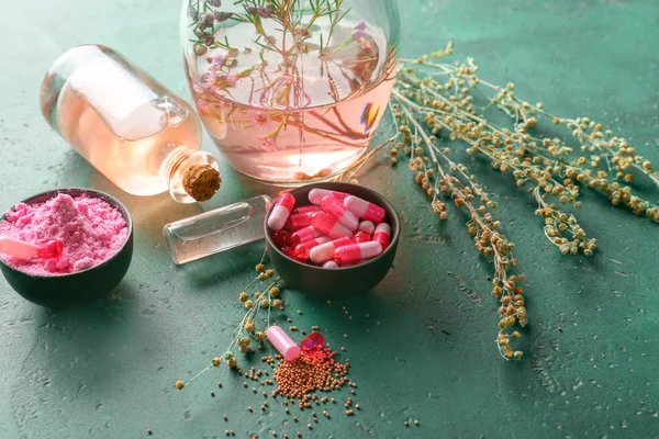 Tigelas com cápsulas, pó e copos de óleo essencial na mesa de cores — Fotografia de Stock