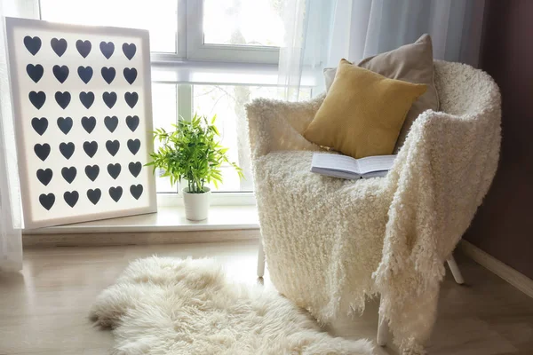 Acogedor sillón con cuadros suaves y libro abierto cerca de la ventana en la habitación —  Fotos de Stock