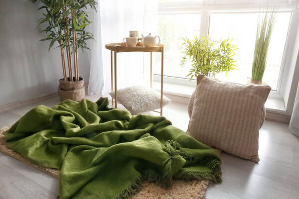 Cozy place for rest with pillows and soft plaid near window in room