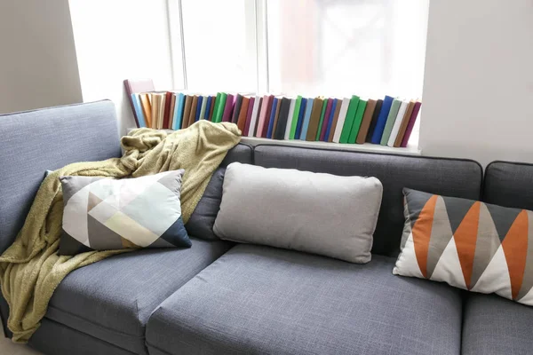 Cozy sofa with soft plaid and pillows near window in room — Stock Photo, Image