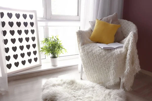 Acogedor sillón con cuadros suaves y libro abierto cerca de la ventana en la habitación —  Fotos de Stock