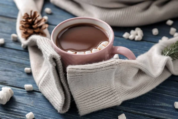Cup of hot chocolate with marshmallows and warm sweater on wooden table — Stock Photo, Image