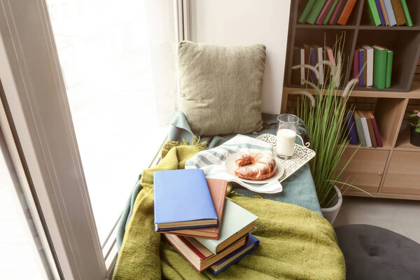 Cozy place for rest with books and tasty breakfast on windowsill