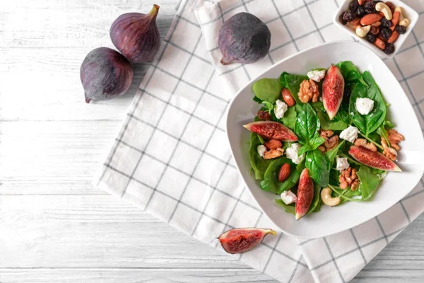 Tányér finom füge salátával, világos fa asztal — Stock Fotó