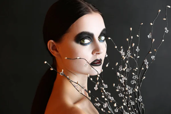 Hermosa mujer con maquillaje de Halloween y ramas sobre fondo oscuro — Foto de Stock