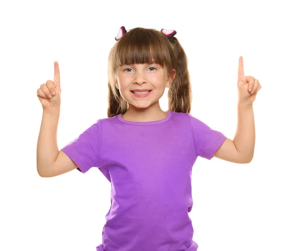 Niña con camiseta apuntando a algo sobre fondo blanco — Foto de Stock