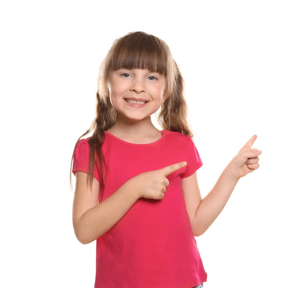 Menina em t-shirt apontando para algo no fundo branco — Fotografia de Stock