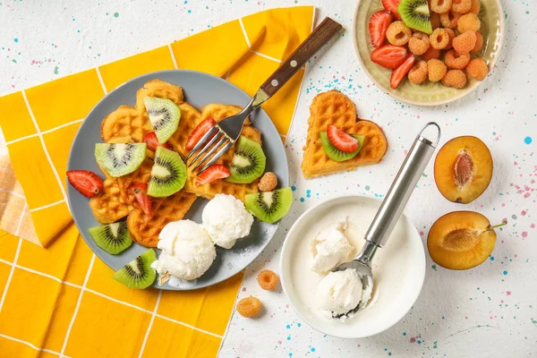 Heart shaped waffles with fruits, berries and ice cream on light table