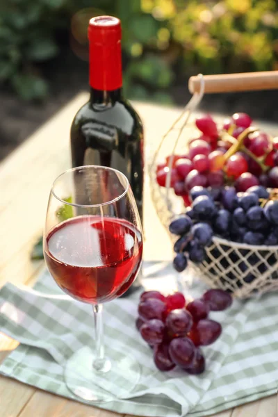 Szkło i butelkę czerwonego wina ze świeżych winogron na drewnianym stole w winnicy — Zdjęcie stockowe