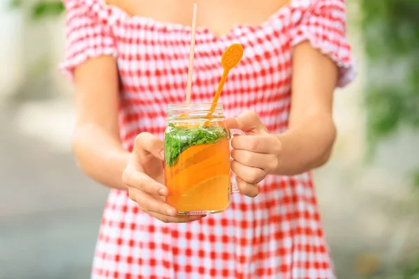 Woman holding mason jar of fresh summer cocktail outdoors, closeup — Stock Photo, Image