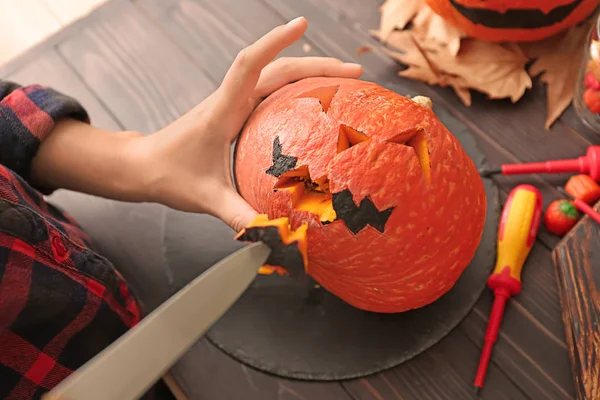 Woman making jack-o-lantern for Halloween party on wooden table, closeup — Stock Photo, Image