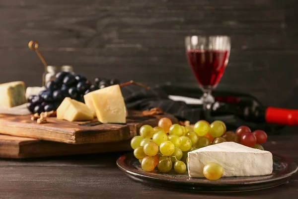 Plato con uvas jugosas frescas maduras y queso brie sobre mesa de madera — Foto de Stock