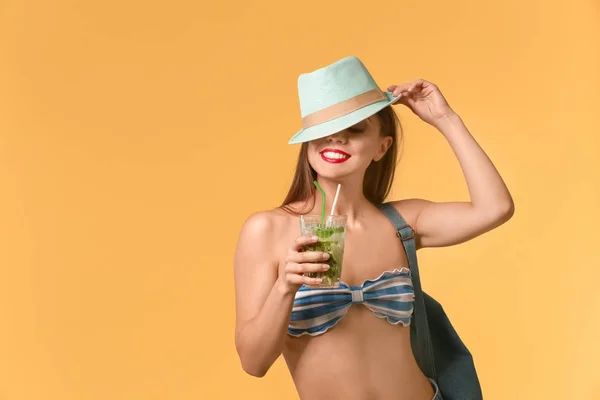 Beautiful woman in swimming suit and with tasty summer cocktail on color background — Stock Photo, Image