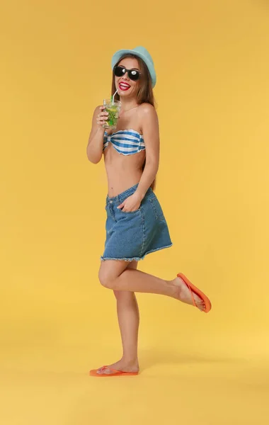 Schöne Frau in Bademode und mit leckeren Sommer-Cocktail auf farbigem Hintergrund — Stockfoto