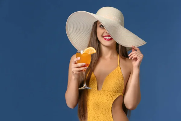 Beautiful woman in swimming suit and with tasty summer cocktail on color background — Stock Photo, Image