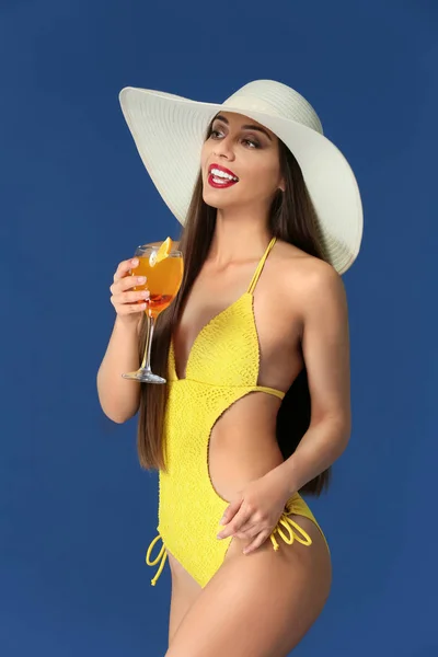 Belle femme en maillot de bain et avec un délicieux cocktail d'été sur fond de couleur — Photo