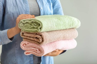 Açık renkli, tatlı temiz yumuşak havlu yığını tutan kadın