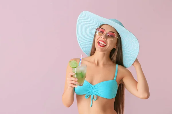 Beautiful woman in swimming suit and with tasty summer cocktail on color background — Stock Photo, Image