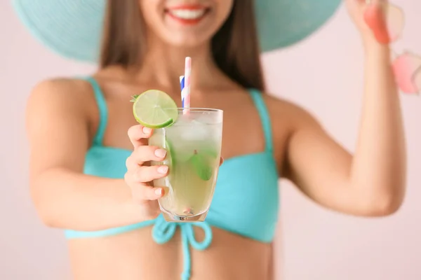 stock image Beautiful woman in swimming suit and with tasty summer cocktail on color background, closeup