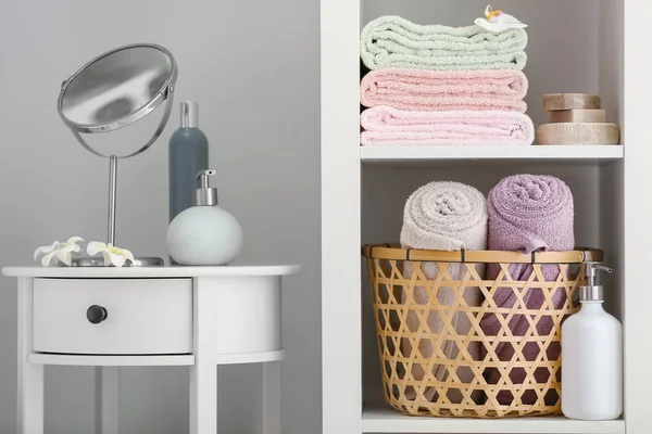 Mesa con productos cosméticos y toallas suaves limpias en los estantes en el baño — Foto de Stock