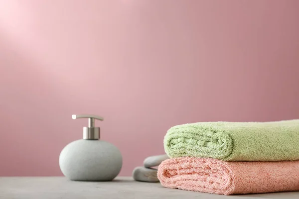 Clean soft towels and soap dispenser on table — Stock Photo, Image