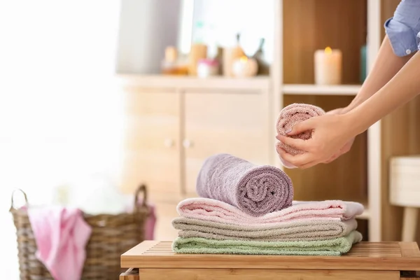 Mulher colocando toalhas macias limpas na mesa no quarto — Fotografia de Stock