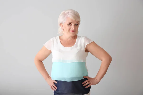 Portrait of mature woman on light background — Stock Photo, Image