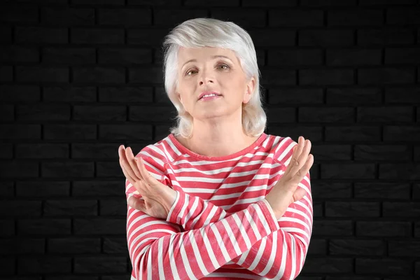 Portrait of mature woman rejecting something on dark background — Stock Photo, Image