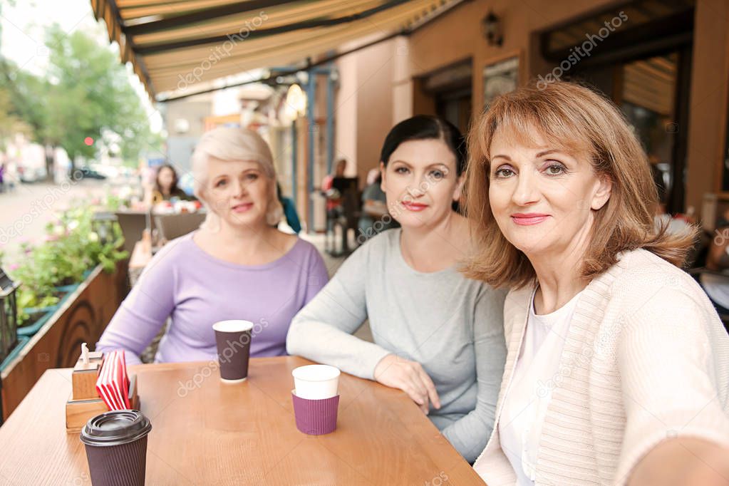 Beautiful mature women taking selfie in cafe