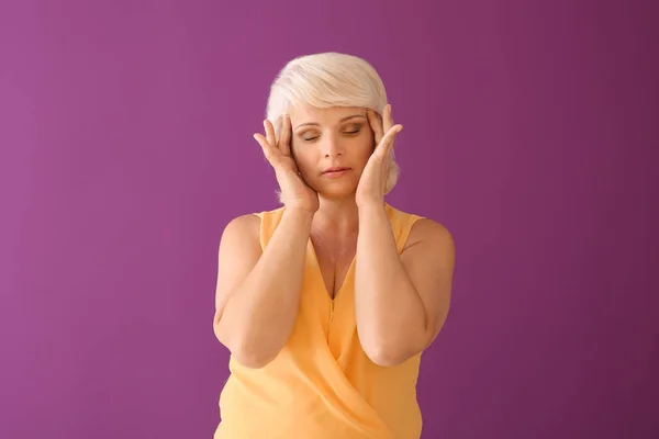 Portrait of mature woman suffering from headache on color background — Stock Photo, Image