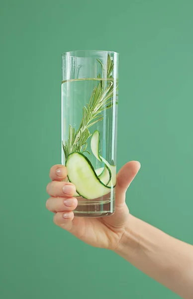 Woman holding glass of fresh cucumber water on color background — Stock Photo, Image