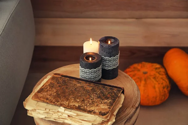 Burning candles and old book for Halloween party on table — Stock Photo, Image